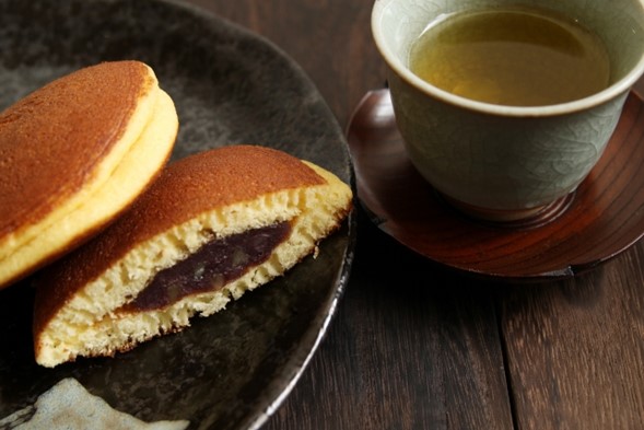 A plate of dorayaki with a cup of green tea on the side