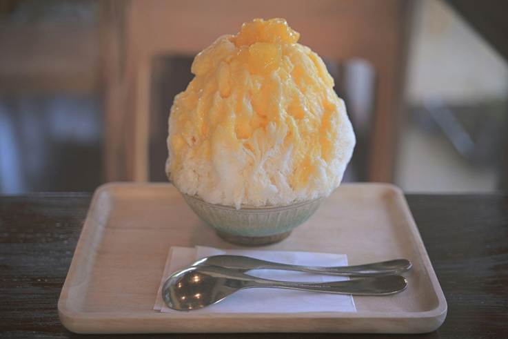 A bowl of shaved iced and two spoons.
