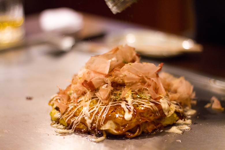 A freshly cooked okonomiyaki pancake on a teppan grill