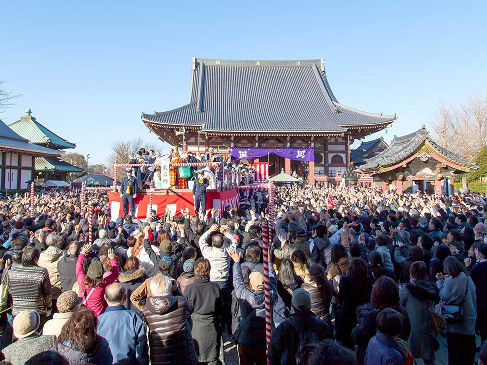 A large crowd gathered in front of a traditional temple hall under a clear sky