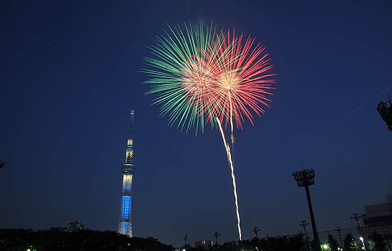 Colorful fireworks lighting up the night sky next to Tokyo Skytree during a vibrant evening display.
