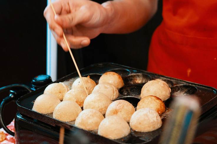 Someone turning takoyaki with a toothpick.