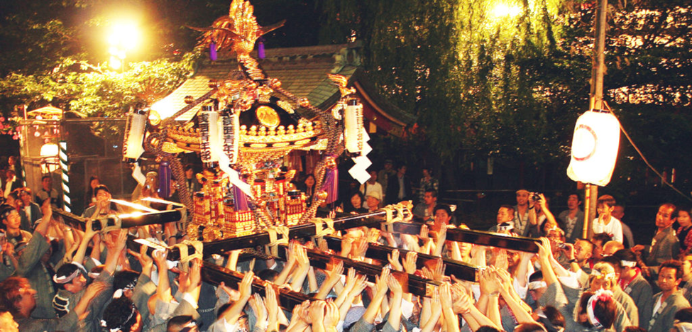 a richly decorated golden mikoshi shrine is hoisted above a crowd of people wearing traditional happi coats