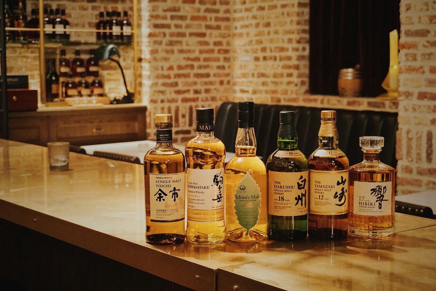 Six bottles of Japanese whisky lined up on a polished wooden bar